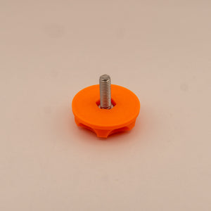 Orange plastic knob with a metal screw on a beige background