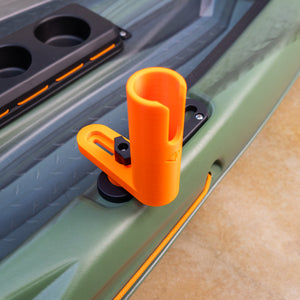 Orange clip attached to a green kayak side with cup holders.