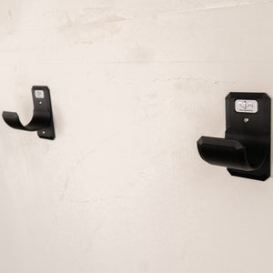 Black wall-mounted rod tube rack on a light beige wall