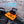 Orange and black kayak mini tool and storage box holder on a kayak's side rail with 'FLEXIBLE PLACEMENT' text above.