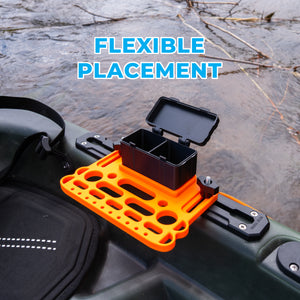 Orange and black kayak mini tool and storage box holder on a kayak's side rail with 'FLEXIBLE PLACEMENT' text above.