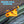 An orange plastic kayak pole storage clip mounted on a green kayak, holding a black pole. Large blue text at the top reads 'SECURE POLE STORAGE,' and white text at the bottom right says '*Pole Not Included'.