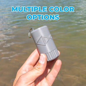 A hand holding a gray cylindrical outdoor accessory with a metal key ring, set against a background of water with a blue text overlay reading 'MULTIPLE COLOR OPTIONS'.