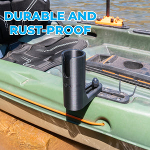 A black net holder on the side of a green kayak, shown outdoors with water and a stakeout pole visible in the background. Large blue text at the top reads 'DURABLE AND RUST-PROOF'.