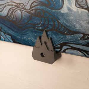 Small gray mountain ski holder on a beige wall with a blue skis on the holder