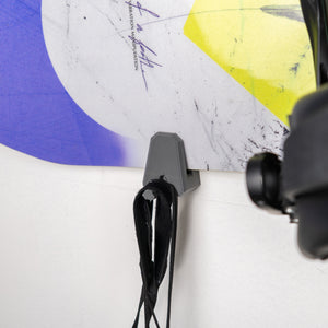 Close-up of gear hanging from a snowboard holder with a white background