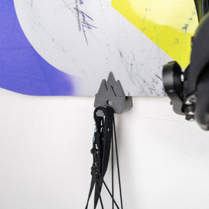 Close-up of gear hanging from a mountain snowboard holder with a white background