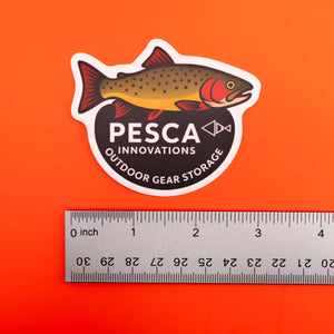 Cutthroat trout and 'PESCA Innovations' sticker on an orange background, accompanied by a ruler for scale, 3 inches wide