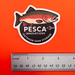 Rainbow trout and 'PESCA Innovations' sticker on an orange background, accompanied by a ruler for scale, 3 inches wide