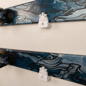 Close-up of a ski with artistic design and a small white ski mount on a light background