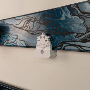 White snowflake-shaped object on a textured surface with a blue and black abstract design in the background.