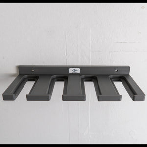 Gray wall-mounted ski pole rack with five hooks on a white wall background