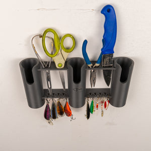 Wall-mounted tool organizer with scissors, pliers, and fishing lures on a white background