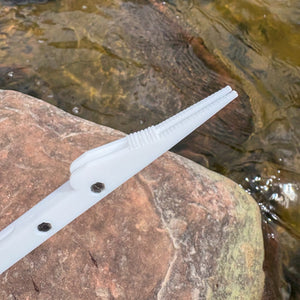 White plastic tool on a rock with water in the background
