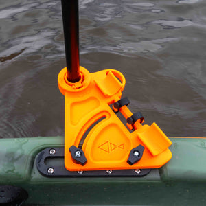 Orange kayak stake-out pole holder mounted on a green fishing kayak rail, securing a black pole over the water.