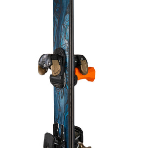 Orange vertical ski hanger by Pesca Innovations with gold and blue ski hanging by binding on a white background.